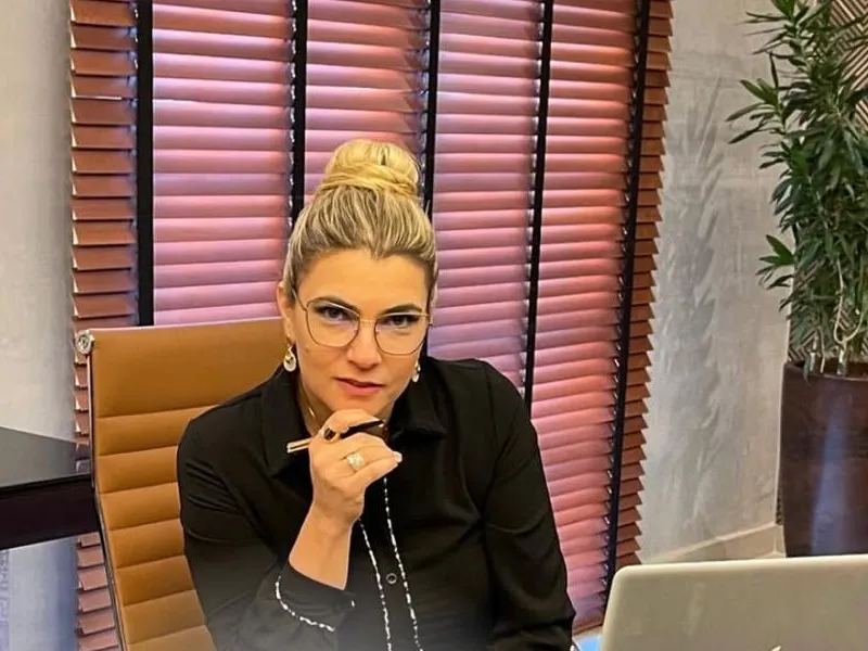 Daniela Bizari à mesa de trabalho, com caneta na mão